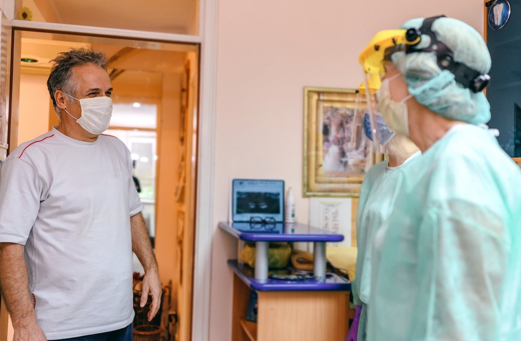 Dentist in PPE greeting patient